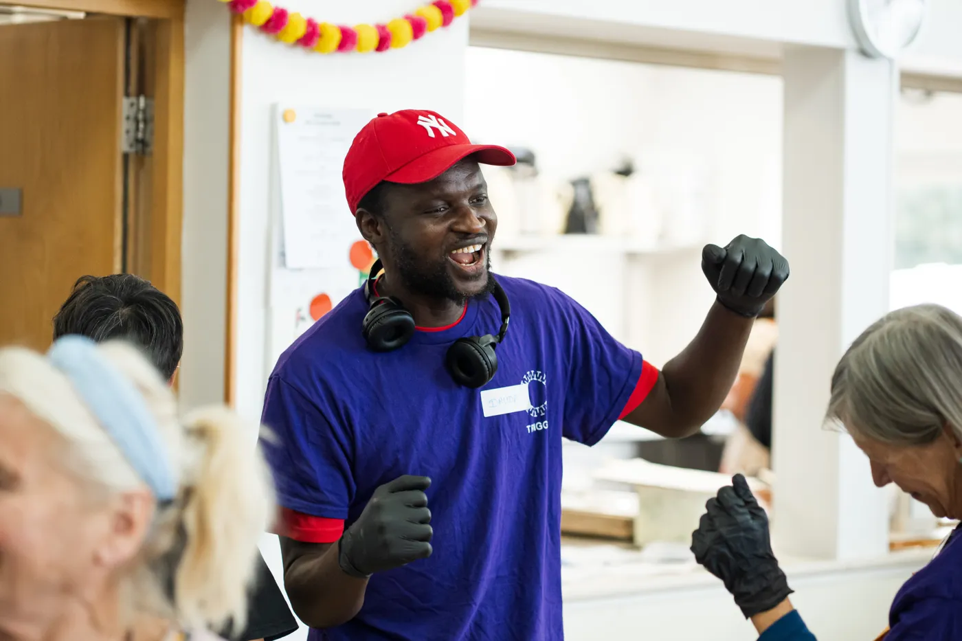 A man in a red cap and purple Trigger T-shirt dancing with gloved fists raised