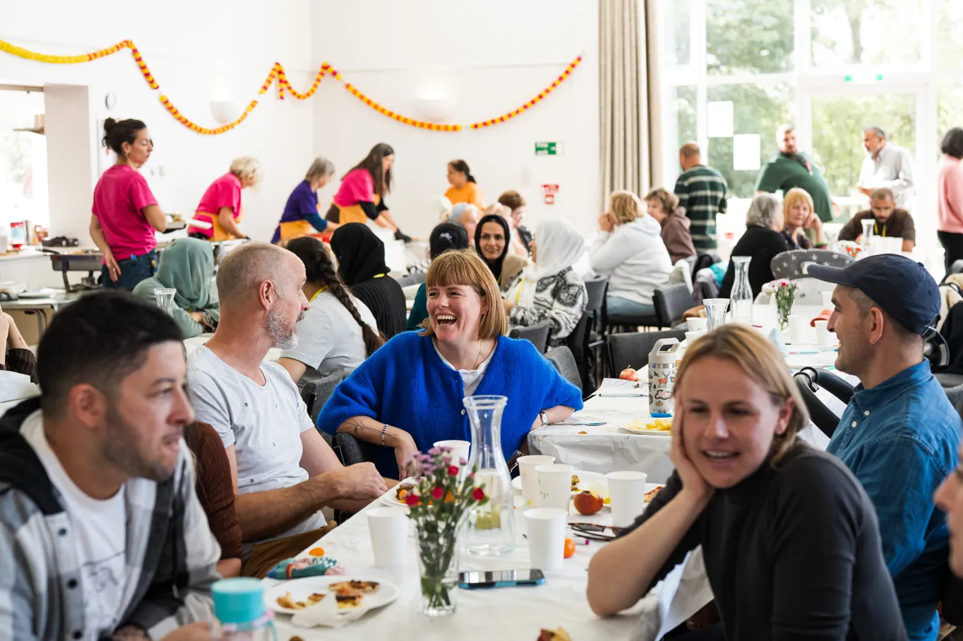 Guests talking and laughing at the tables in Shipham Village Hall during FEASTING.